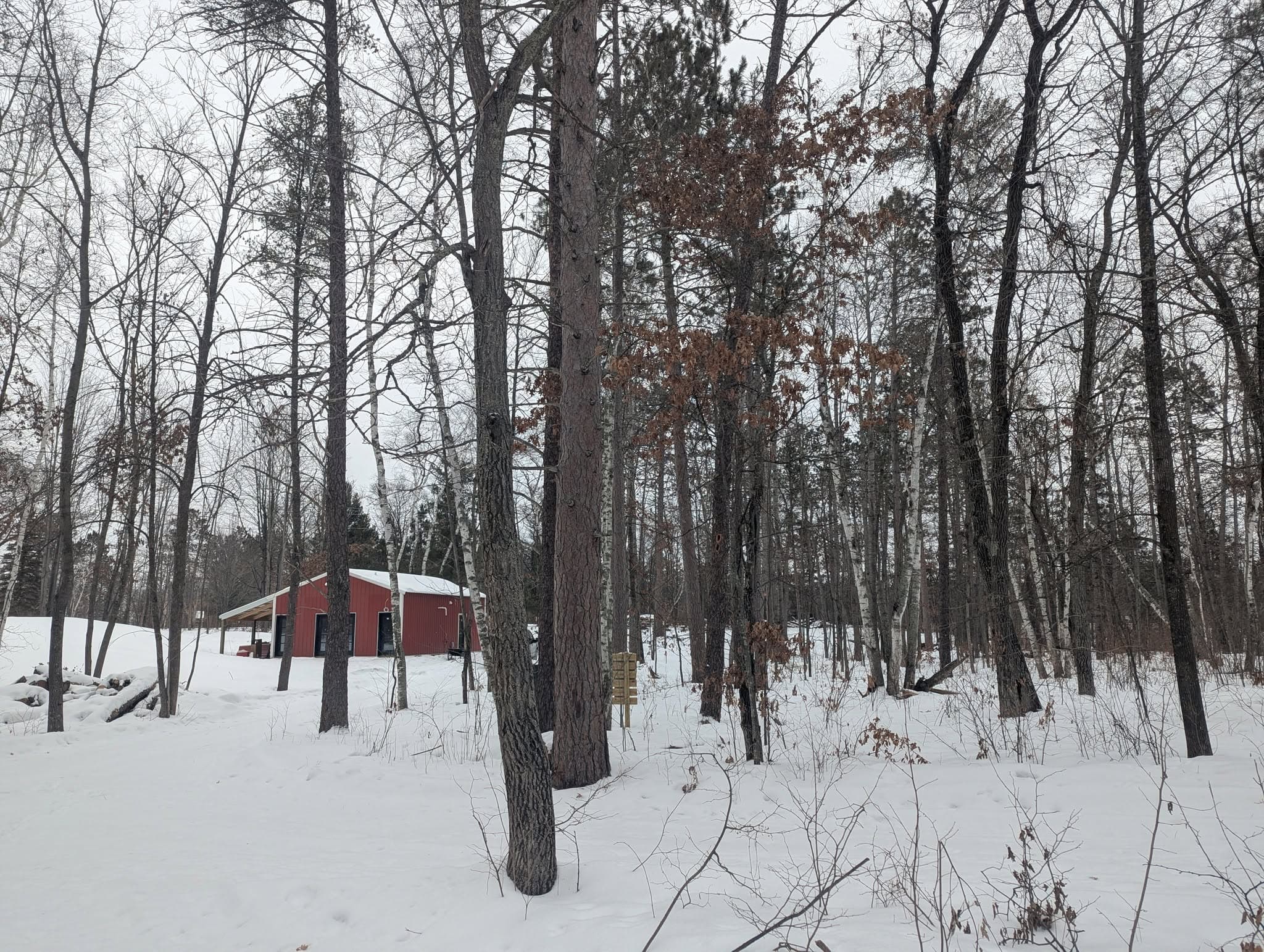 Red building with white roof in snowy forest clearing