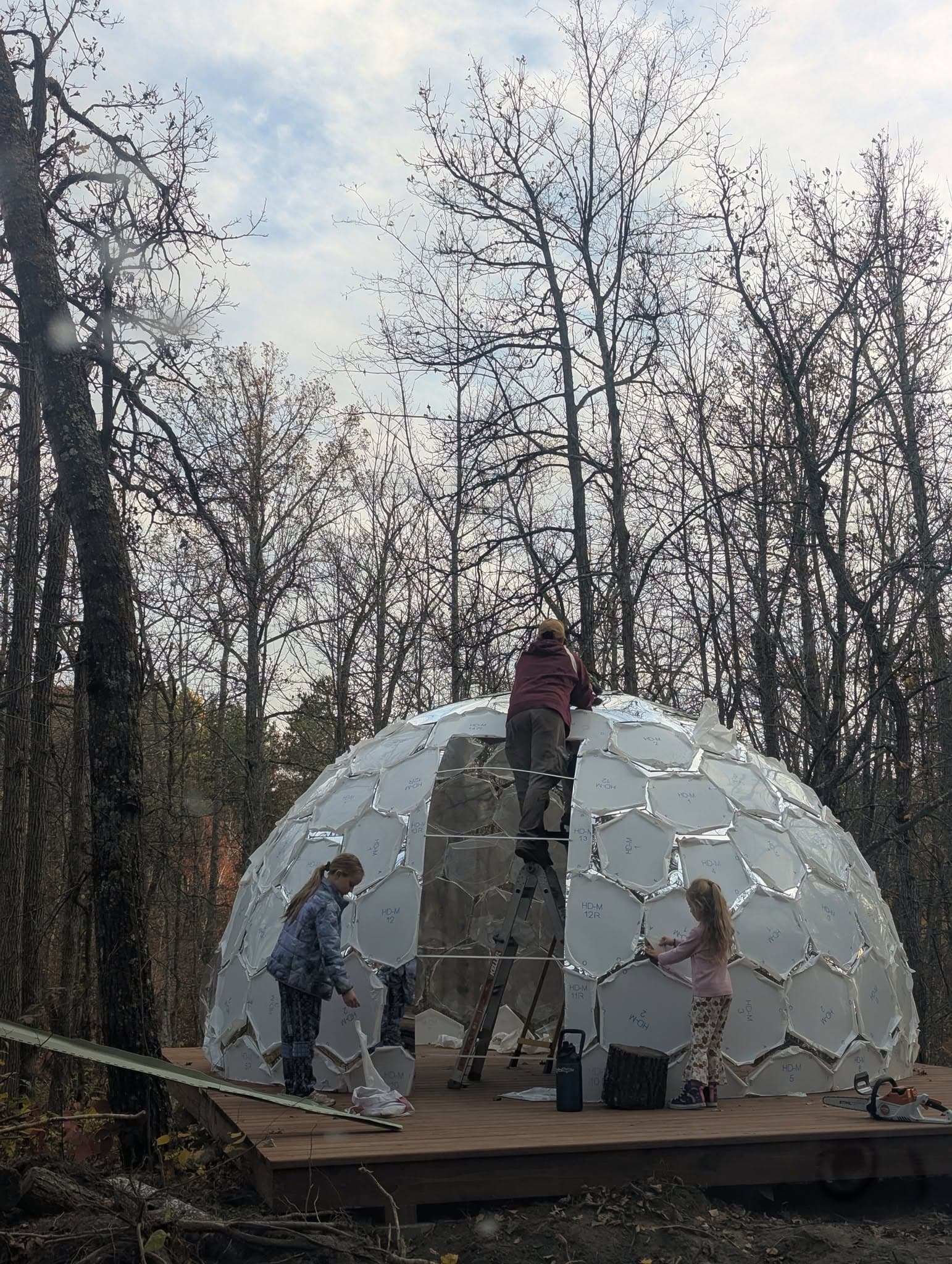 Family enjoying a geodesic dome with transparent panels and forest views