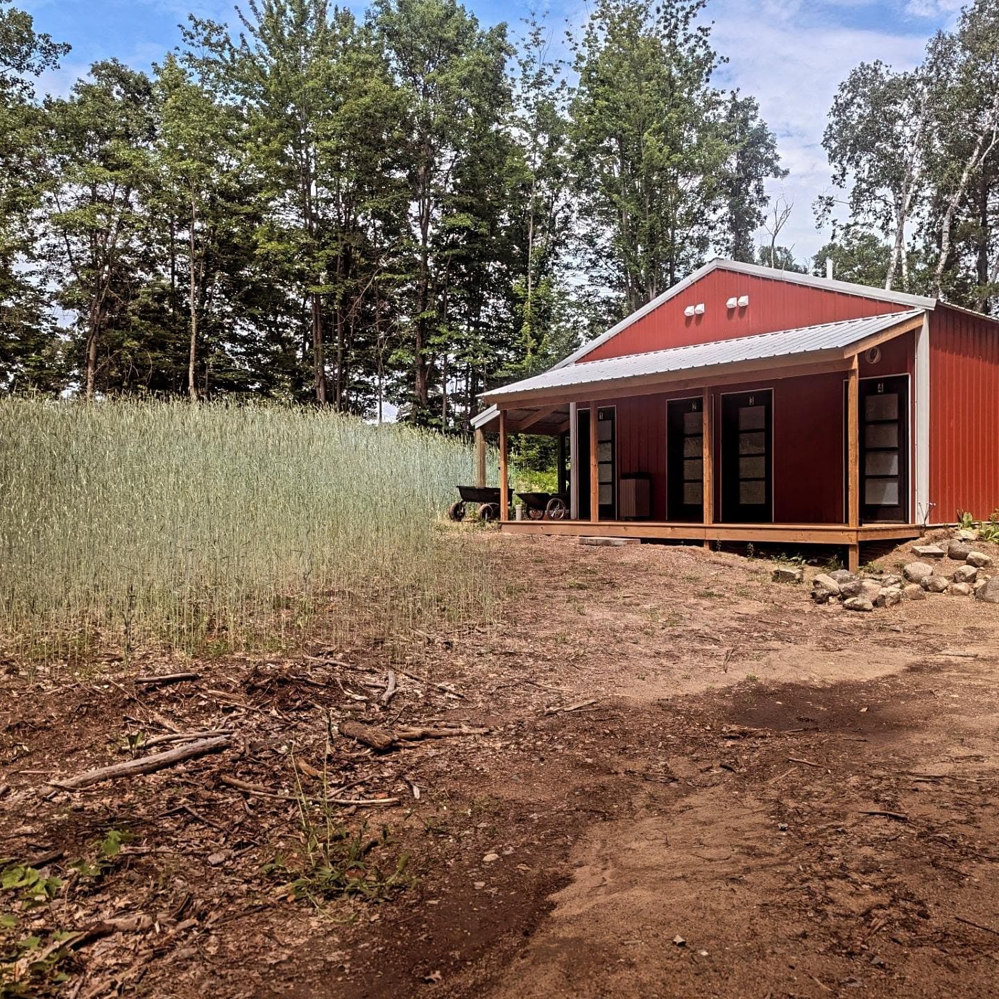 Red corrugated metal cabin with large windows on a wooden deck